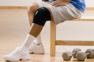 Man with knee brace gesturing the ok symbol in health club
