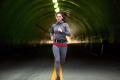 Woman jogging on run through city downtown tunnel street lights